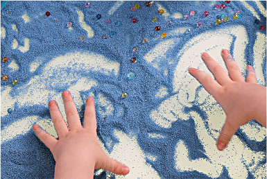 A child's hands in blue sand